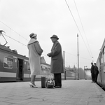 168254 Afbeelding van twee treinreizigers op het perron van het N.S.-station Amsterdam C.S. te Amsterdam, met op de ...